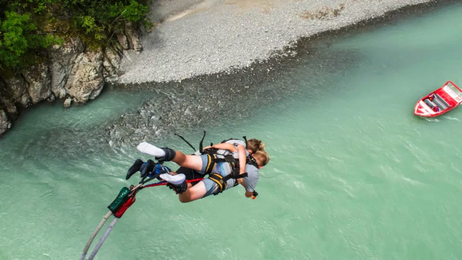 Two people tandem bungy jumping together over the Waiau River in Hanmer Springs