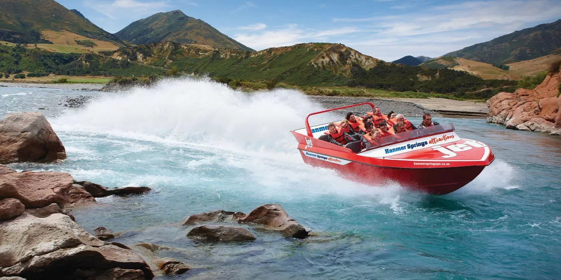 High-speed Hanmer Springs jet boat tour hugging a rocky bend on the Waiau River