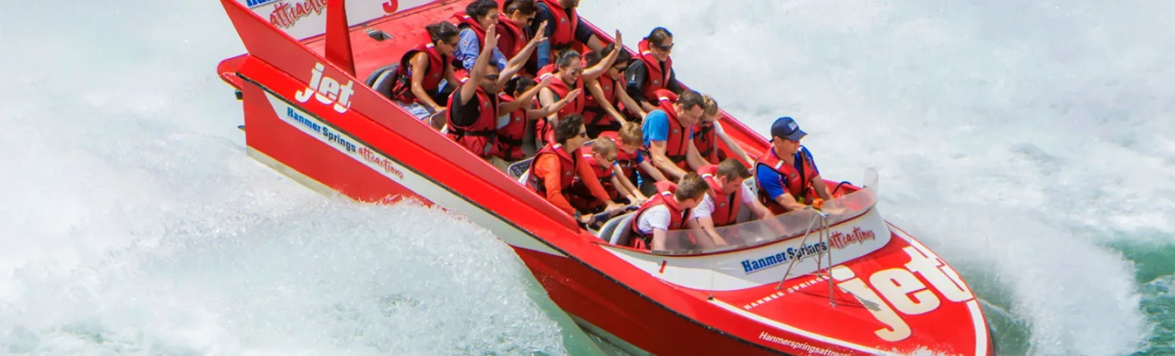 Hanmer Springs jet boat performing a 360-degree spin on the Waiau River, creating a splash around thrilled passengers
