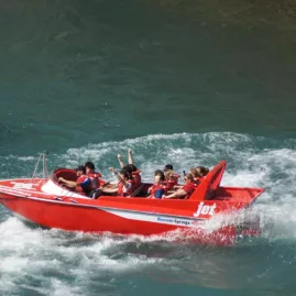 Hanmer Springs jet boat mid-spin on the Waiau River, thrilling passengers in red life jackets