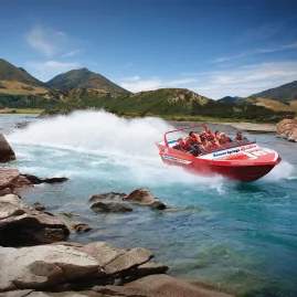 High-speed Hanmer Springs jet boat tour hugging a rocky bend on the Waiau River