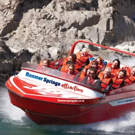 Jet boat speeding through river rapids at Hanmer Springs Attractions with excited passengers