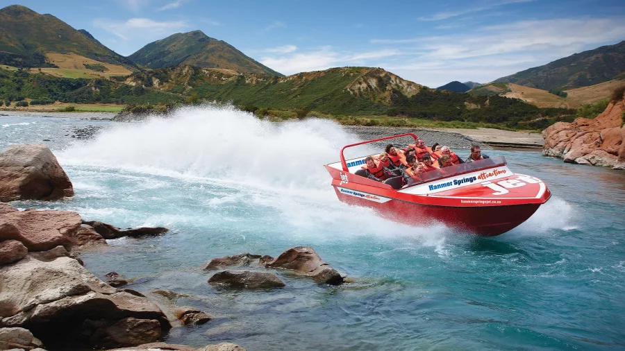 High-speed Hanmer Springs jet boat tour hugging a rocky bend on the Waiau River