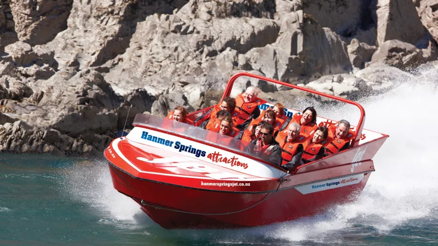 Jet boat speeding through river rapids at Hanmer Springs Attractions with excited passengers