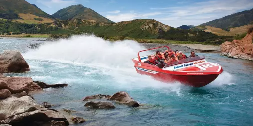 High-speed Hanmer Springs jet boat tour hugging a rocky bend on the Waiau River