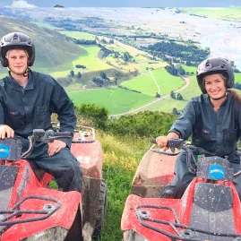 Two quad bikers sitting on their ATVs overlooking Hanmer’s high country and winding river