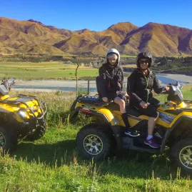Family on two yellow quad bikes with two children riding pillion on each in Hanmer Springs, with mountains in the background