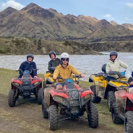 Group of quad bikers posing beside a river with mountain ranges in the background in Hanmer Springs