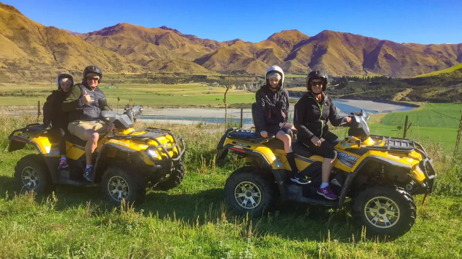 Family on two yellow quad bikes with two children riding pillion on each in Hanmer Springs, with mountains in the background