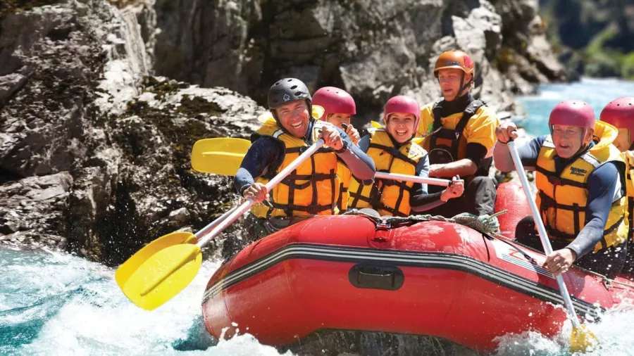 Rafters powering through gentle rapids with big smiles on a Hanmer Springs Attractions rafting tour