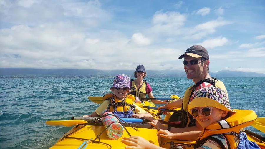 Happy children paddling with their parents on a family kayak tour in Kaikōura, South Island