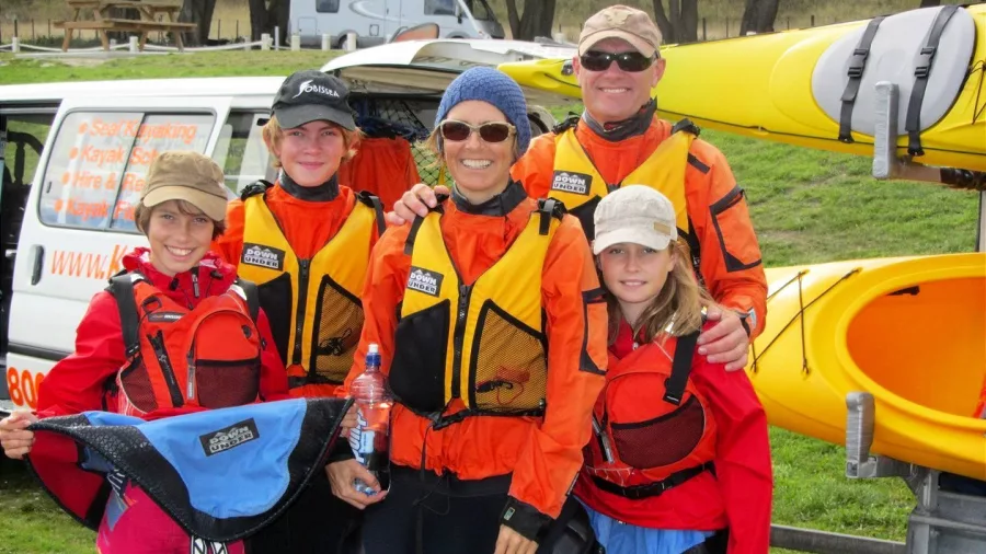 A family of five posing in front of kayaks in Kaikōura before heading out on the water