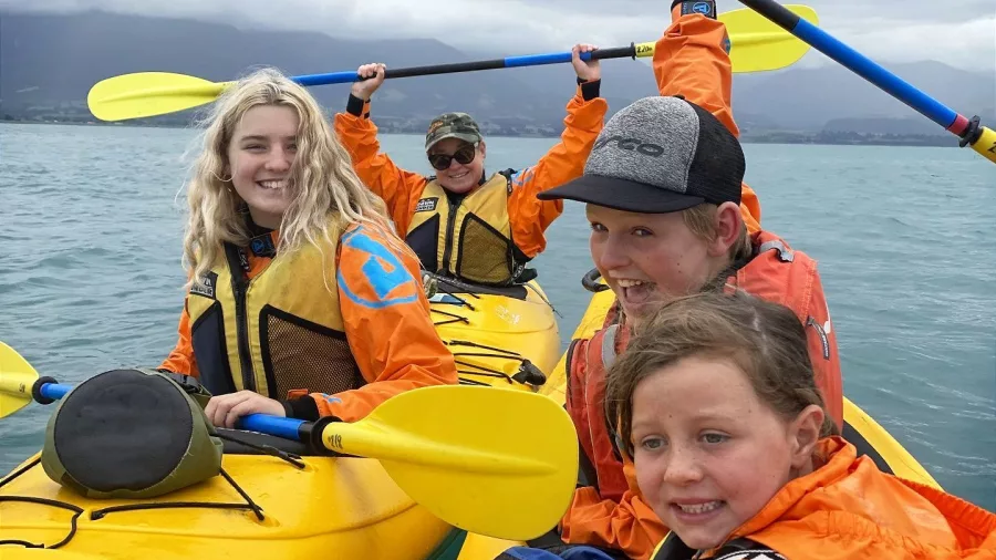 Kids and adults laughing together in double kayaks on a family kayak tour in Kaikōura