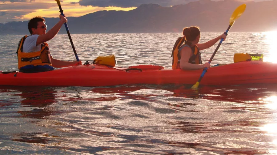 Silhouetted kayak pair floating on still water at dusk near Kaikōura, South Island