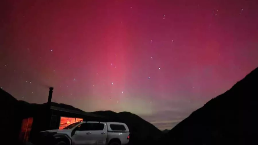 Aurora Australis glowing pink over mountains at Hanmer Springs stargazing site