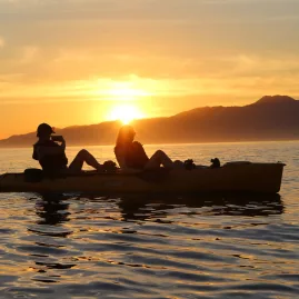 Two people silhouetted in a kayak during a vibrant Kaikōura sunset