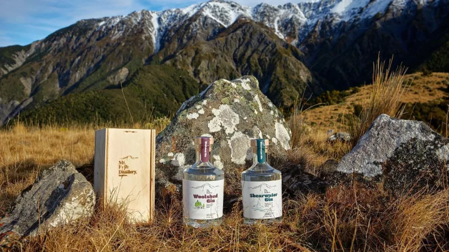 Woolshed and Shearwater Gin bottles in front of snow-covered Kaikōura mountains