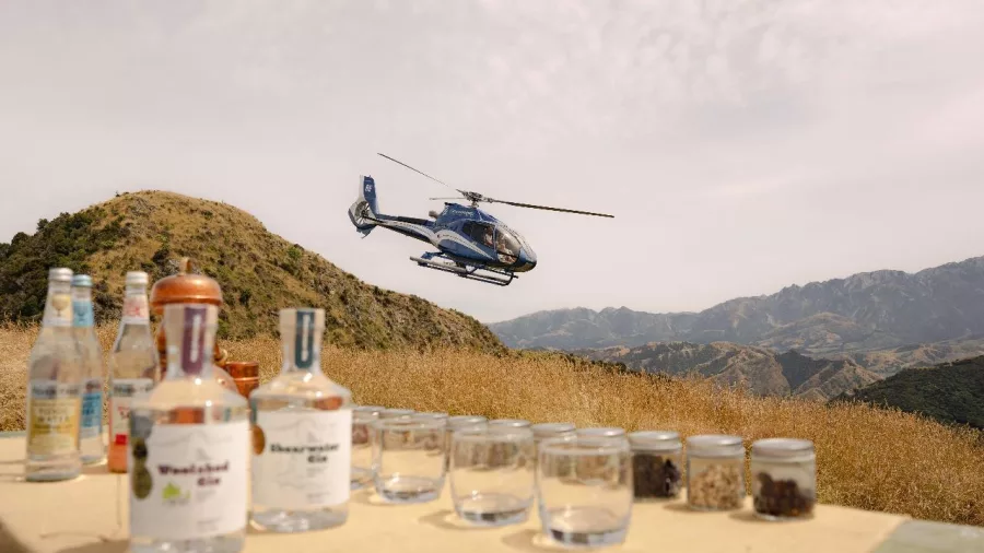 Helicopter landing beside gin tasting setup in Kaikōura’s Seaward Ranges