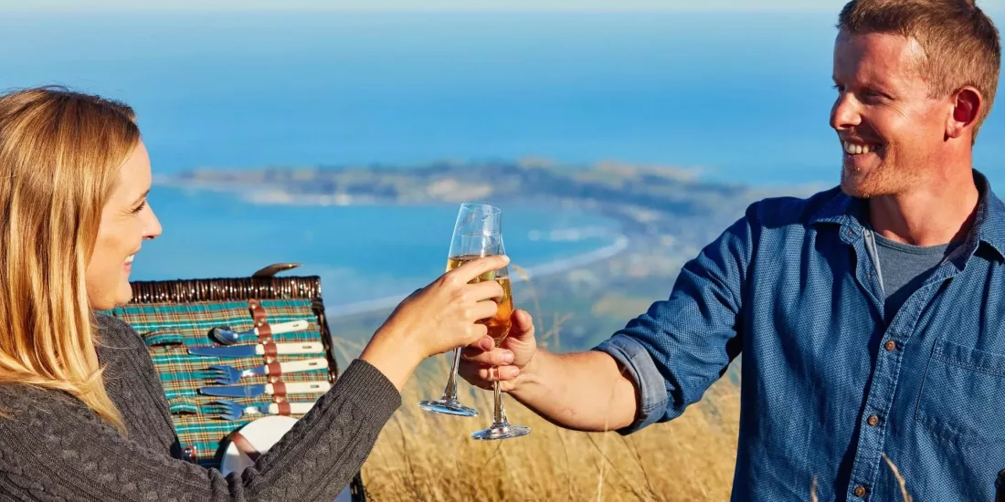 Couple toasting during a romantic Mt Fyffe heli-picnic overlooking the Kaikōura coast