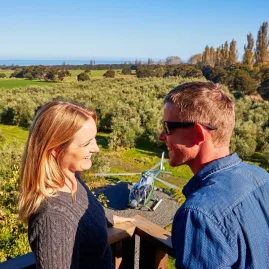Couple enjoying views with helicopter landing at olive grove near Kaikōura