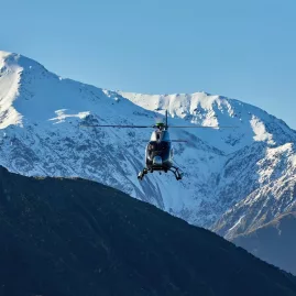 Helicopter flying past snow-covered peaks near Mt Fyffe in Kaikōura