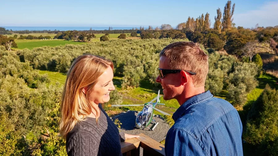 Couple enjoying views with helicopter landing at olive grove near Kaikōura