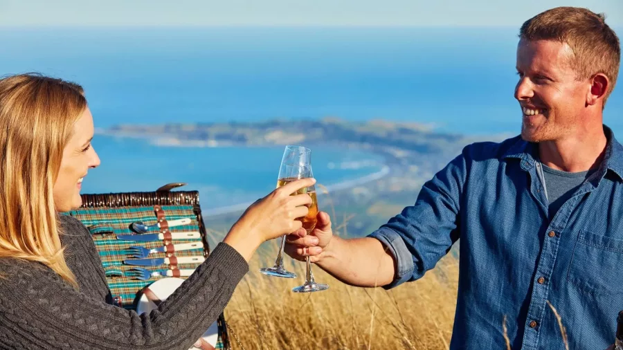 Couple toasting during a romantic Mt Fyffe heli-picnic overlooking the Kaikōura coast