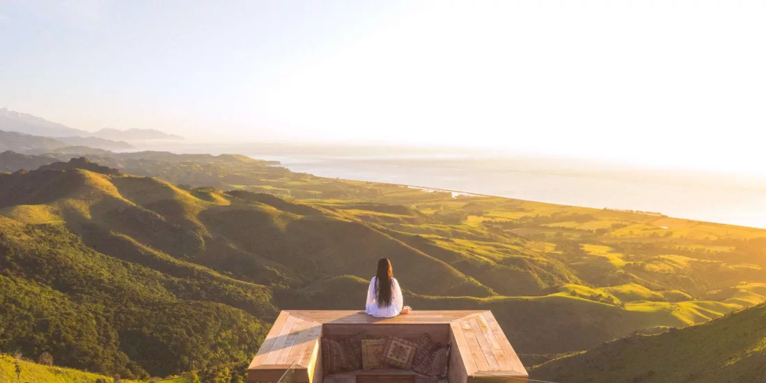 Woman enjoying the sunrise from a private viewing deck at Matai Peak, Kaikōura