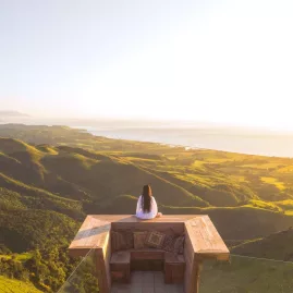 Woman enjoying the sunrise from a private viewing deck at Matai Peak, Kaikōura