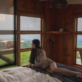Woman relaxing inside the bedroom at Matai Peak with sweeping ocean views