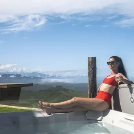 Woman in a spa pool with mountain and ocean views at Matai Peak retreat