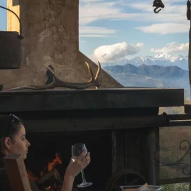 Woman relaxing by the fireplace at Matai Peak with stunning alpine views