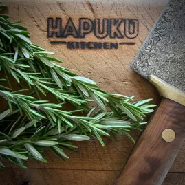 Close-up of rosemary and Damascus knife on Hapuku Kitchen chopping board in Kaikōura