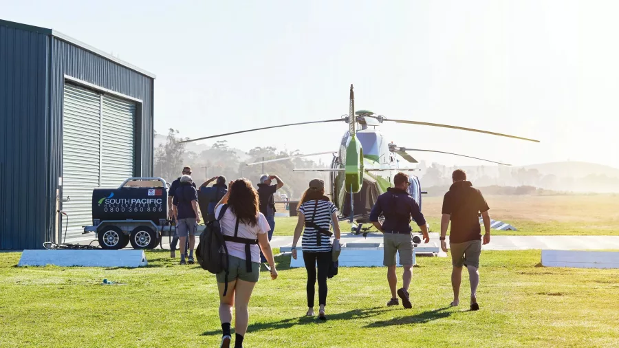 Passengers walking toward South Pacific Helicopters for a scenic Kaikōura flight
