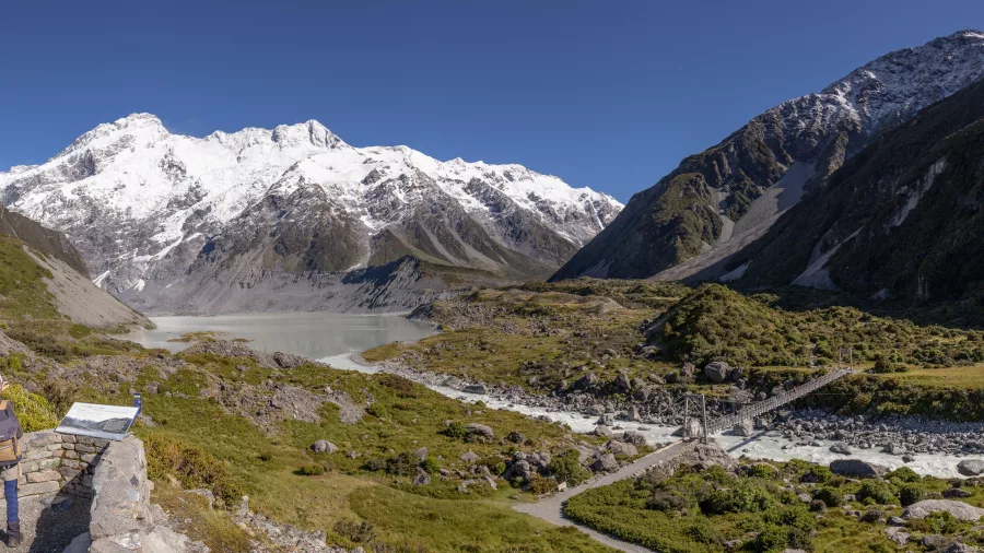 Hikers admiring Mueller Lake and swingbridge on the Hooker Valley Track
