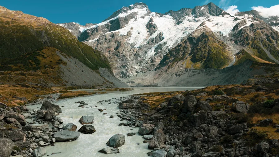 Glacial river flowing through Hooker Valley with snow-covered Aoraki / Mount Cook in the background.