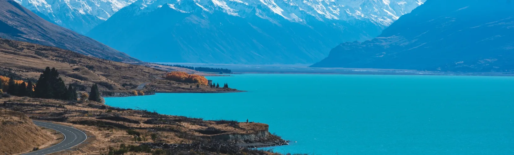 Aoraki/Mount Cook rising above Lake Pukaki with a clear blue sky and snow-covered peaks