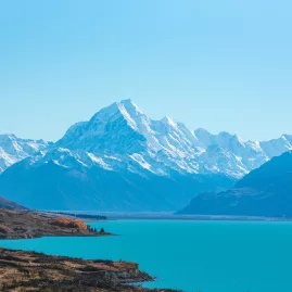 Aoraki/Mount Cook rising above Lake Pukaki with a clear blue sky and snow-covered peaks