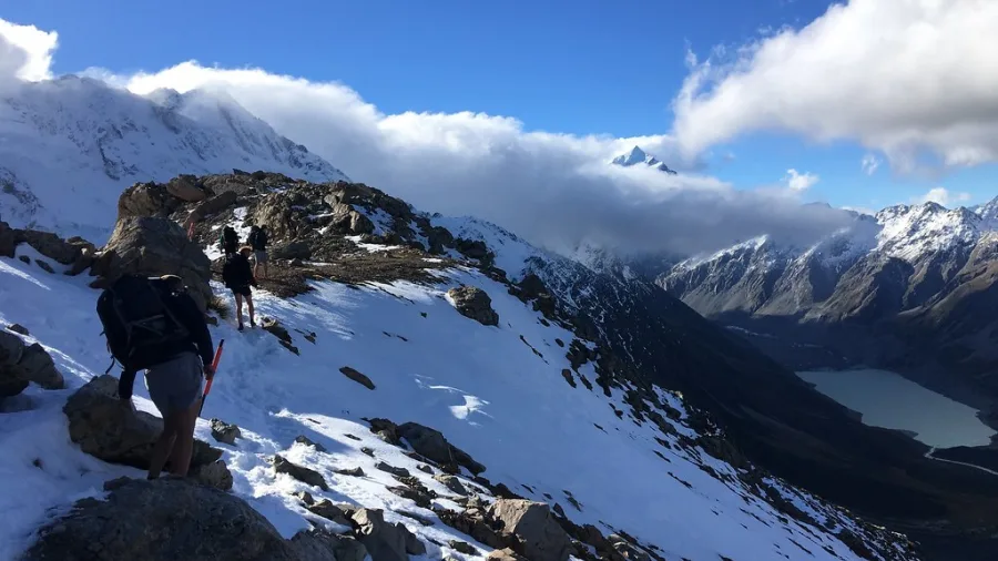 Hikers making their way along the snowy Mueller Track on the Sealy Range in Aoraki/Mount Cook National Park.