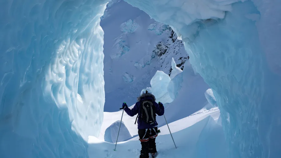 Person wearing snowshoes exploring an ice cave on the Tasman Glacier near Aoraki/Mount Cook.