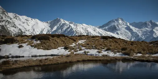 Snow-capped peaks of Aoraki Mount Cook reflected in the Red Tarns with tussock and alpine landscape, New Zealand