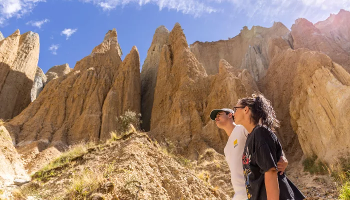 Couple walking among the towering Clay Cliffs in Ōmarama, New Zealand