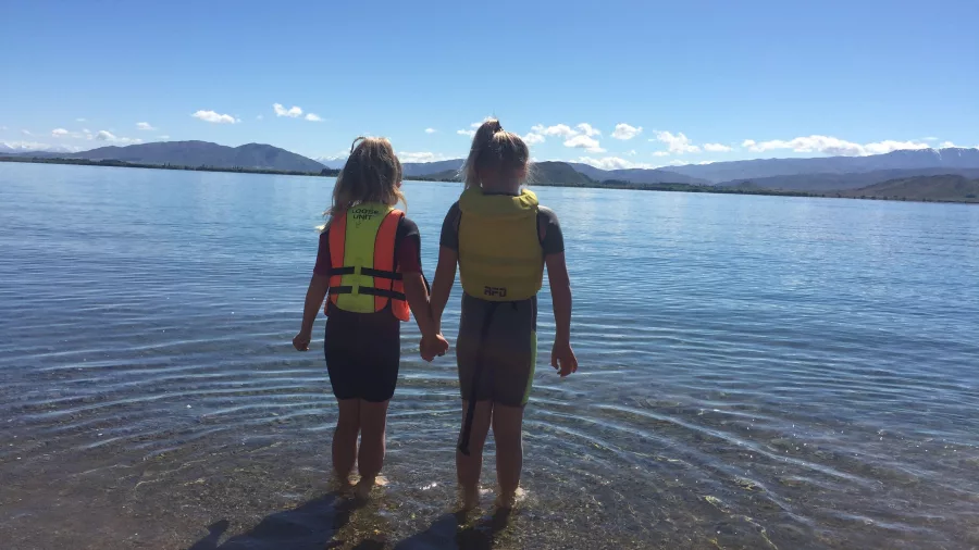 Children paddling in shallow waters at Lake Benmore, New Zealand