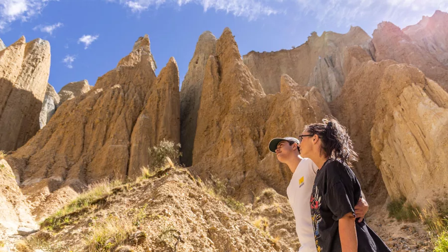 Couple walking among the towering Clay Cliffs in Ōmarama, New Zealand