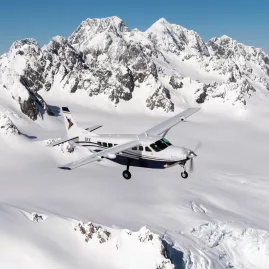 Scenic flight aircraft cruising above glacier fields in New Zealand’s Southern Alps