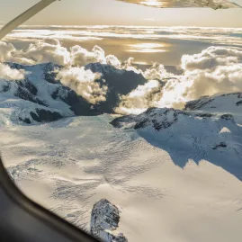 Sunset over Franz Josef Glacier névé captured from aircraft window during scenic flight