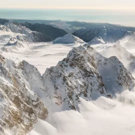 Snow-covered Southern Alps with Canterbury coastline in the distance during scenic flight