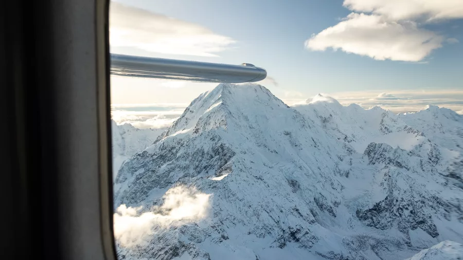 Passenger view through aircraft window of snow-covered Mt Cook peak