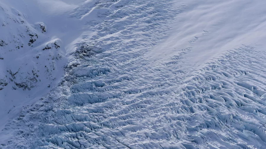 Aerial close-up of glacial crevasses and blue ice on a South Island glacier