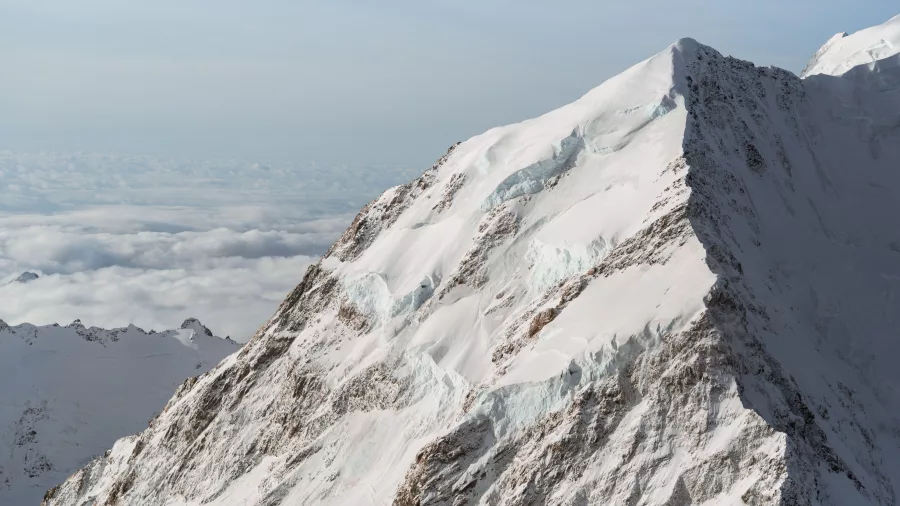 Close aerial shot of Mt Cook’s icefalls and crevassed ridgeline under blue skies